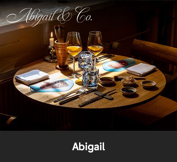 Dukat bord med vin, glas och smårätter i restaurangmiljö hos Abigail