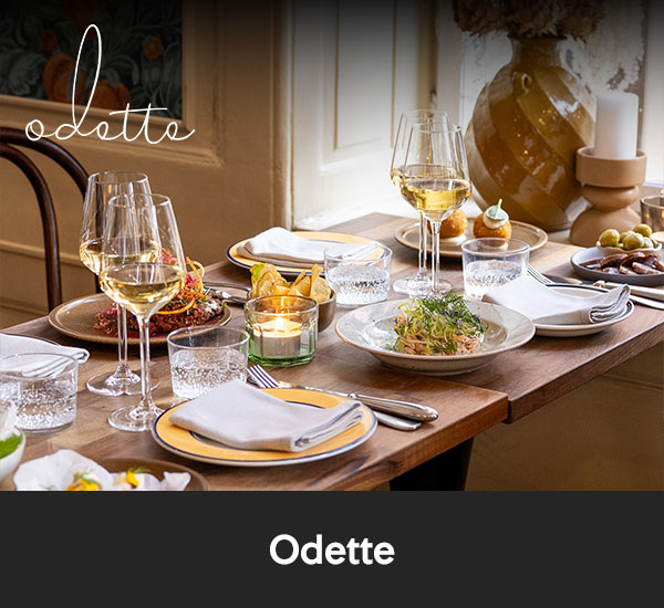 Dukat bord med vin, glas och rätter i varm restaurangmiljö hos Odette