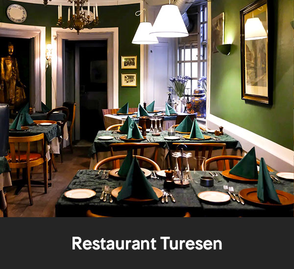 Dukat restaurangrum med gröna väggar och bord med servetter uppställda för middag på Restaurant Turesen