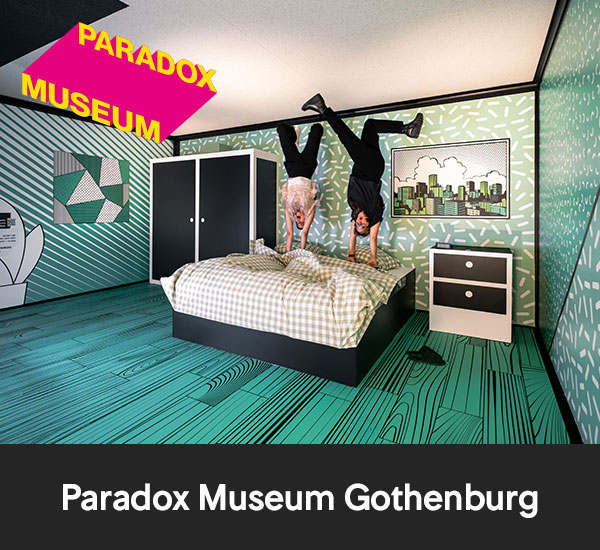 Personer som står upp och ner i rum med optisk illusion hos Paradox Museum